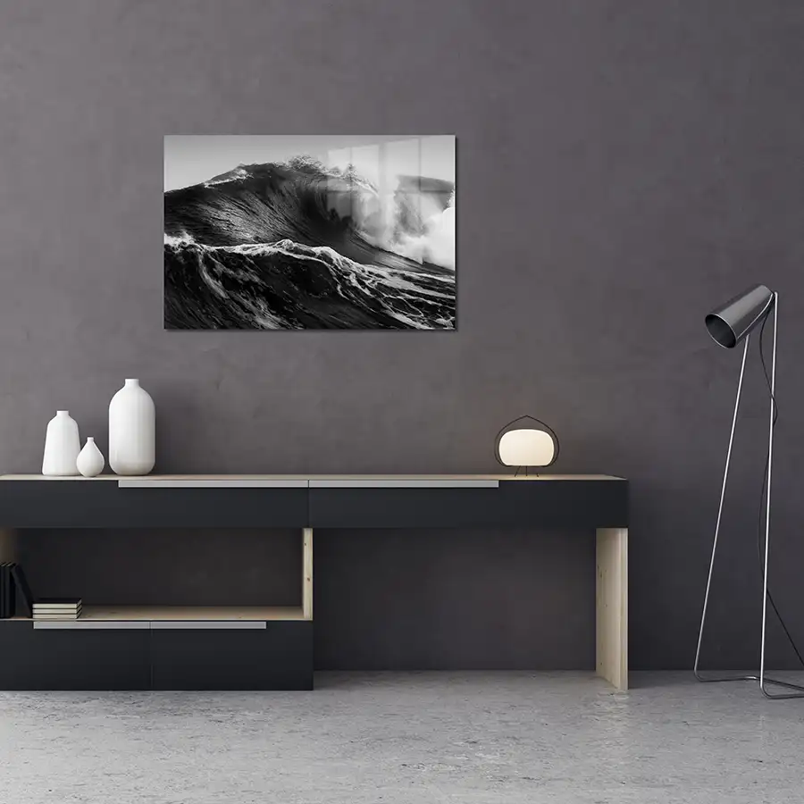 176565696_lifestyle A landscape black and white glass print hanging on a wall of a roaring wave spraying sea water dramatically into the air.