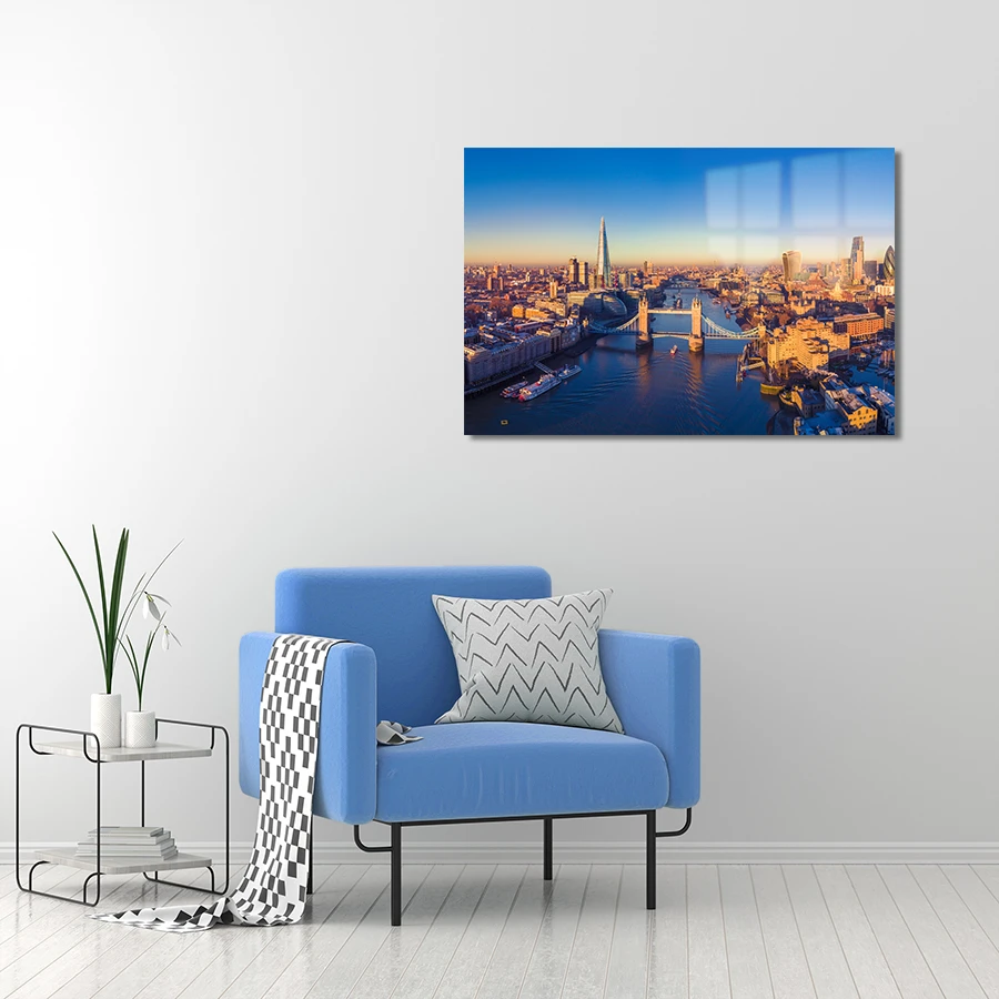 132796360-london-river-thames-lifestyle panoramic glass wall art of golden hour in London, with the iconic Tower Bridge hanging on the wall above a blue armchair